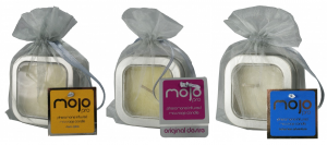 Three massage candles wrapped in gray mesh gift bags, each with a different-colored tag reading "Mojo"