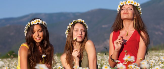 Three beautiful girlfriends playing on camomile meadow