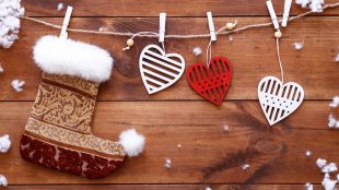 Christmas stocking and white red hearts hanging on brown wooden background with snow