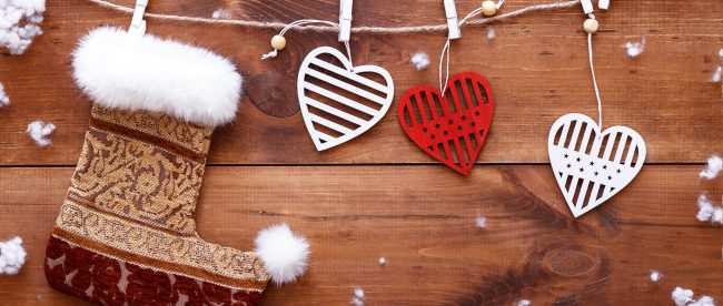 Christmas stocking and white red hearts hanging on brown wooden background with snow