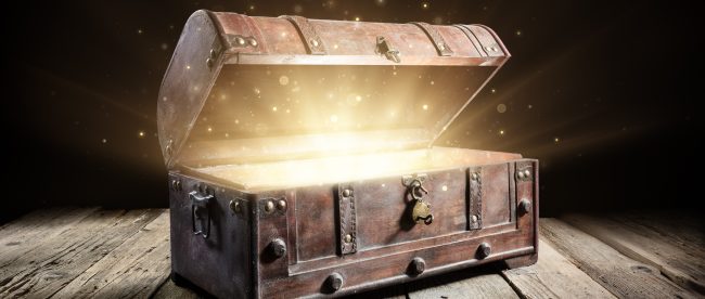 A vintage wooden treasure chest opens to reveal a glowing interior and sparkles