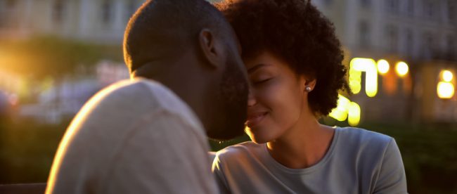 Black couple leaning close for a kiss on an evening date