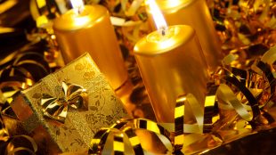Golden candles and streamers on a table that also holds a gold-wrapped small gift