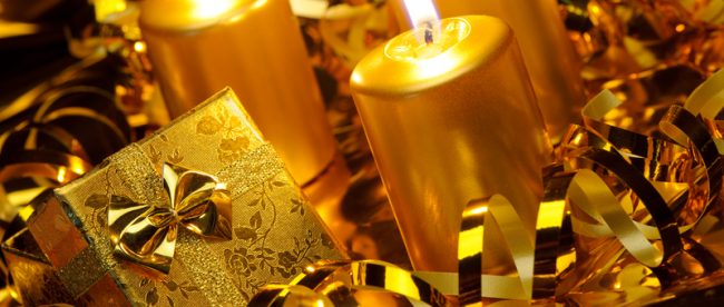 Golden candles and streamers on a table that also holds a gold-wrapped small gift