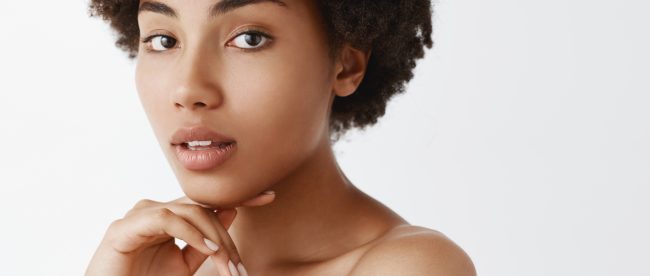 Beautiful woman looking at the camera and resting her chin on the back of her fingers. Her mouth is slightly open