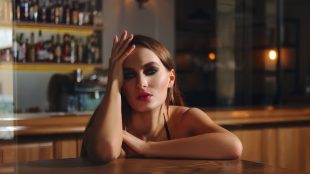 Seductive woman in a bar leaning flirtatiously on a table