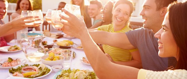 A group of friends clinking glasses at a summer barbeque at sunset